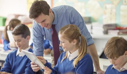 Teacher speaking with two seated students.