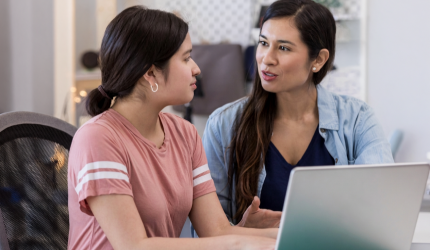 Two people talking while sitting in front of a laptop